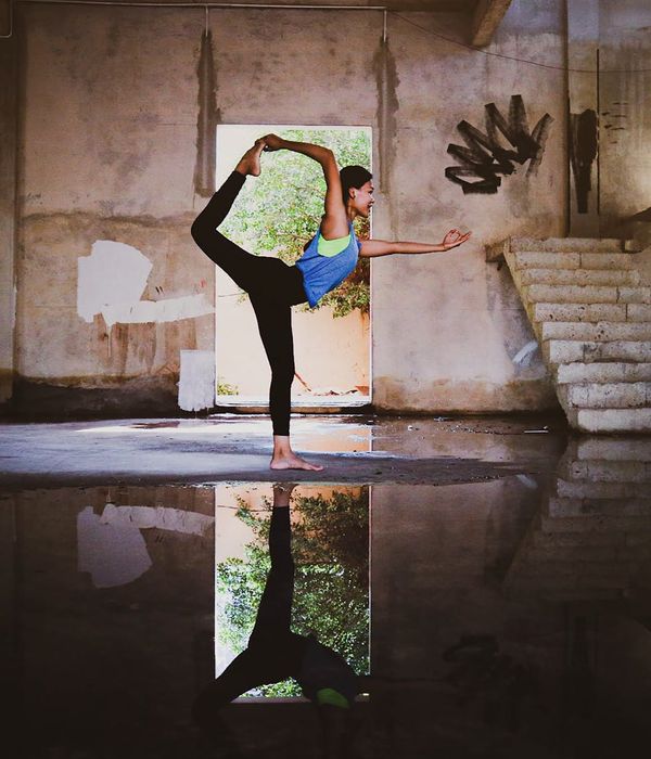 Woman in a graceful yoga pose with warm light filtering through a window.